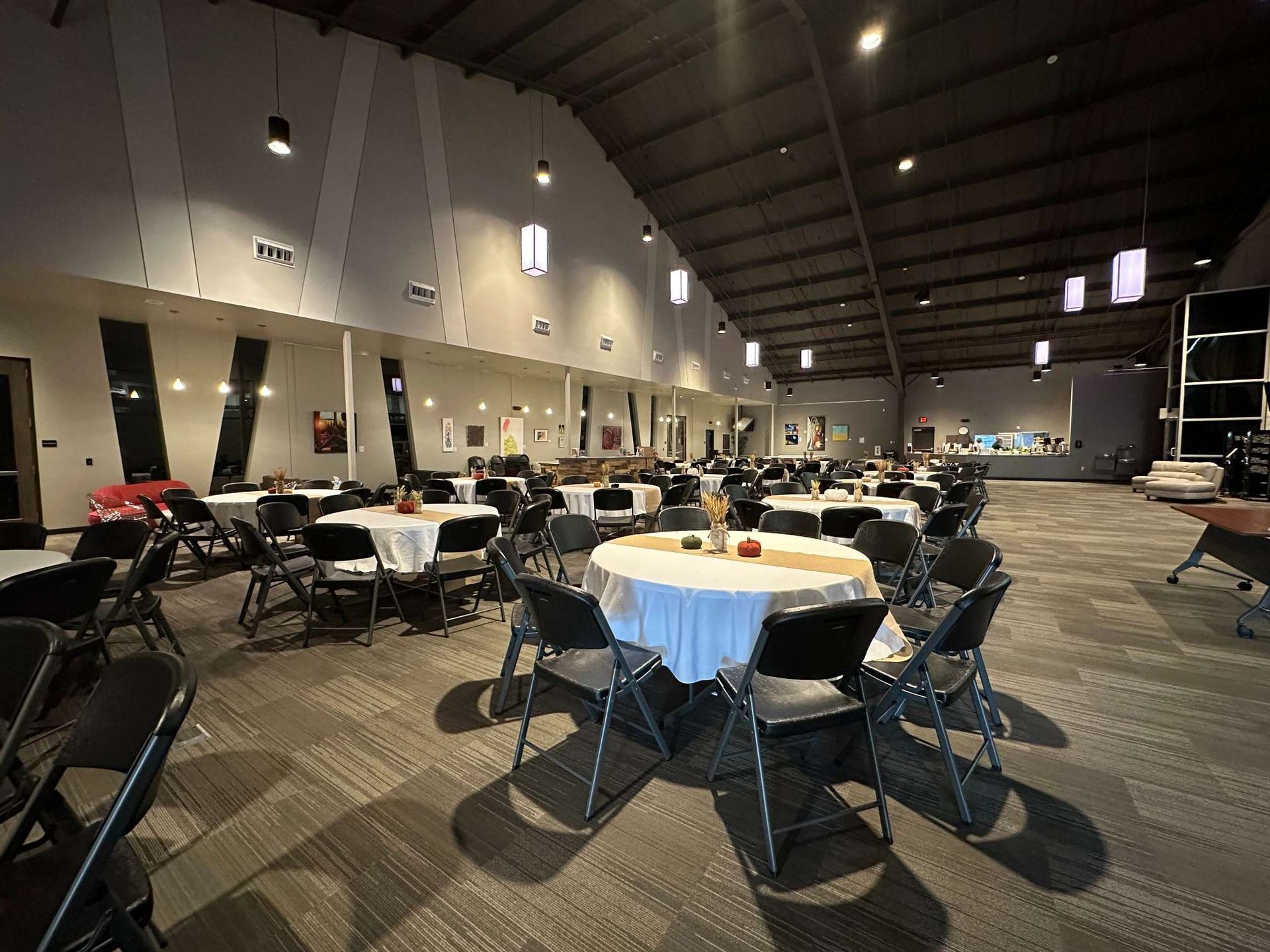 A large room with tables and chairs set up for a wedding reception.