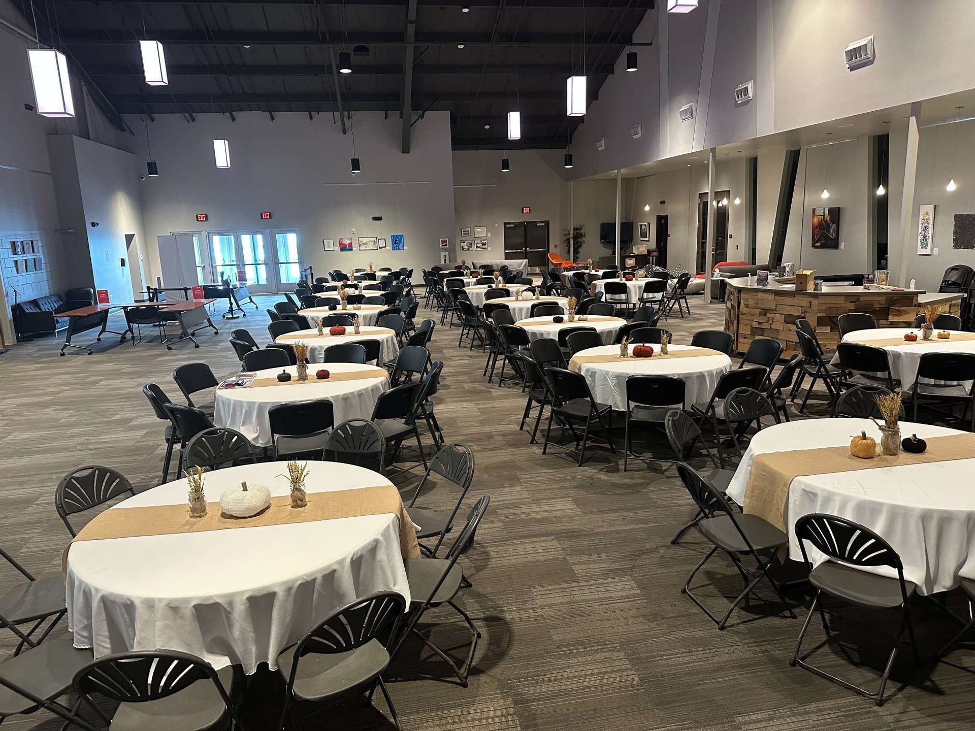 A large room with tables and chairs set up for a wedding reception.