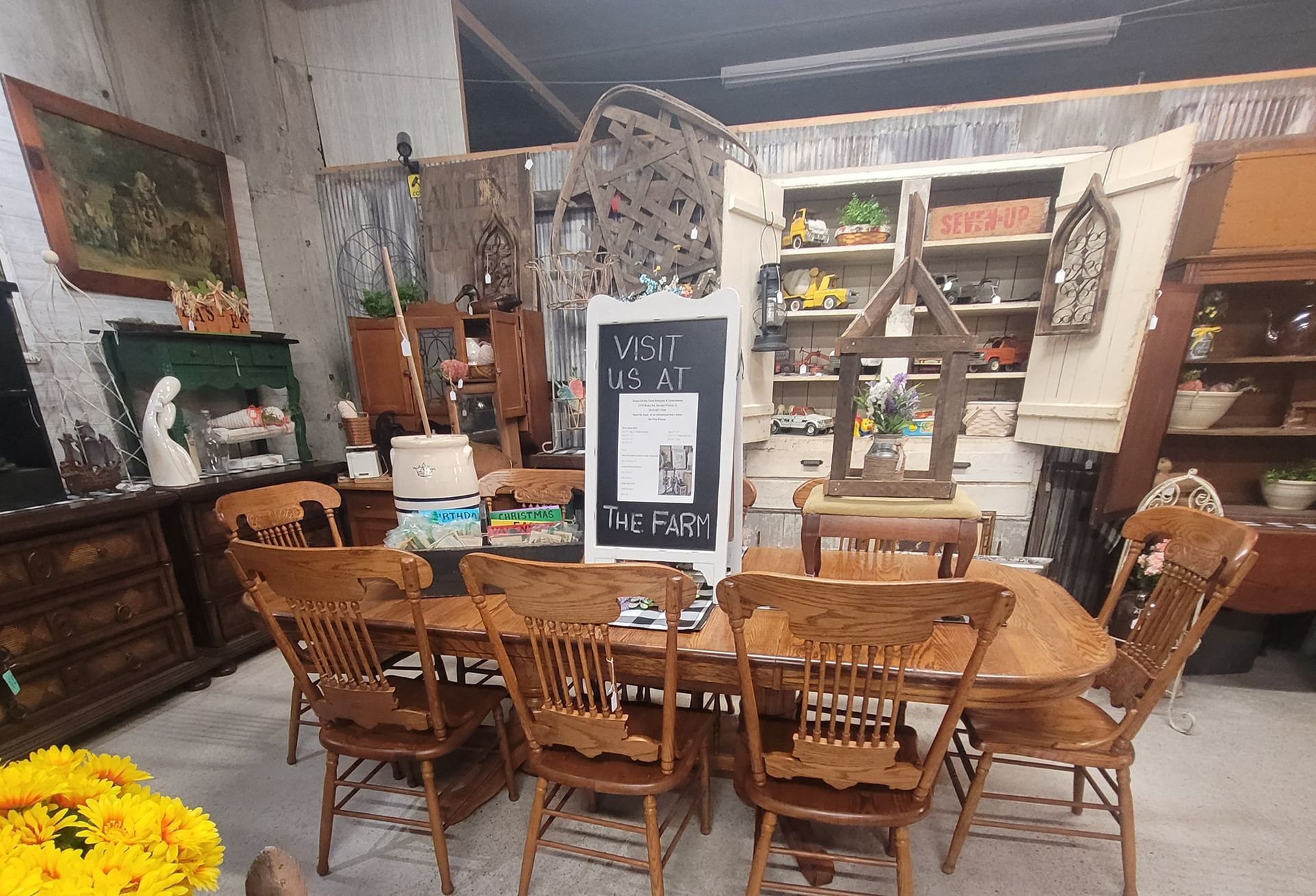 Antique furniture display: dining table with chairs, cabinets, wall art, and decor.