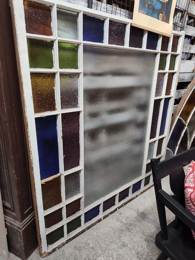White-framed window with a large, frosted central pane and a border of small, colorful stained glass squares.