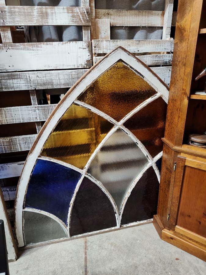 Stained glass window with arched top; white frame; brown, yellow, blue, and clear panes.