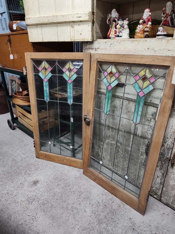 Two antique stained glass windows with a turquoise, pink, and yellow design against a clear background.