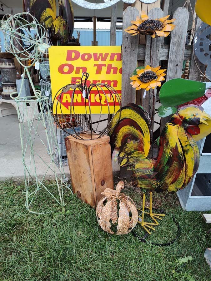 Antique shop display with metal rooster, sunflowers, and pumpkin.