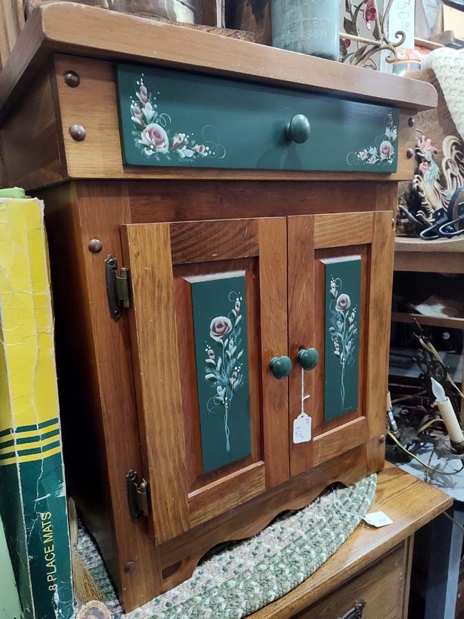Wooden cabinet with green painted accents and floral design.