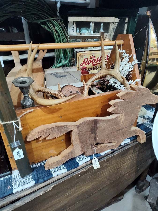 Wooden box with antlers, a carved fox, and other vintage items on display.