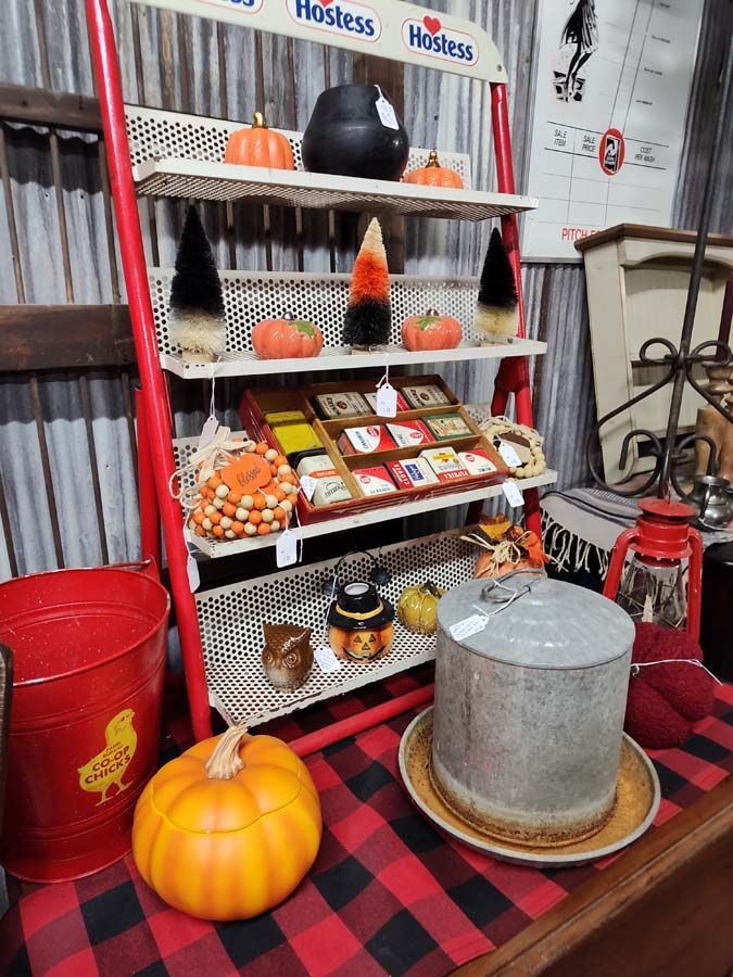 A display of autumn decorations on shelves, including pumpkins, candy corn, and a cauldron.