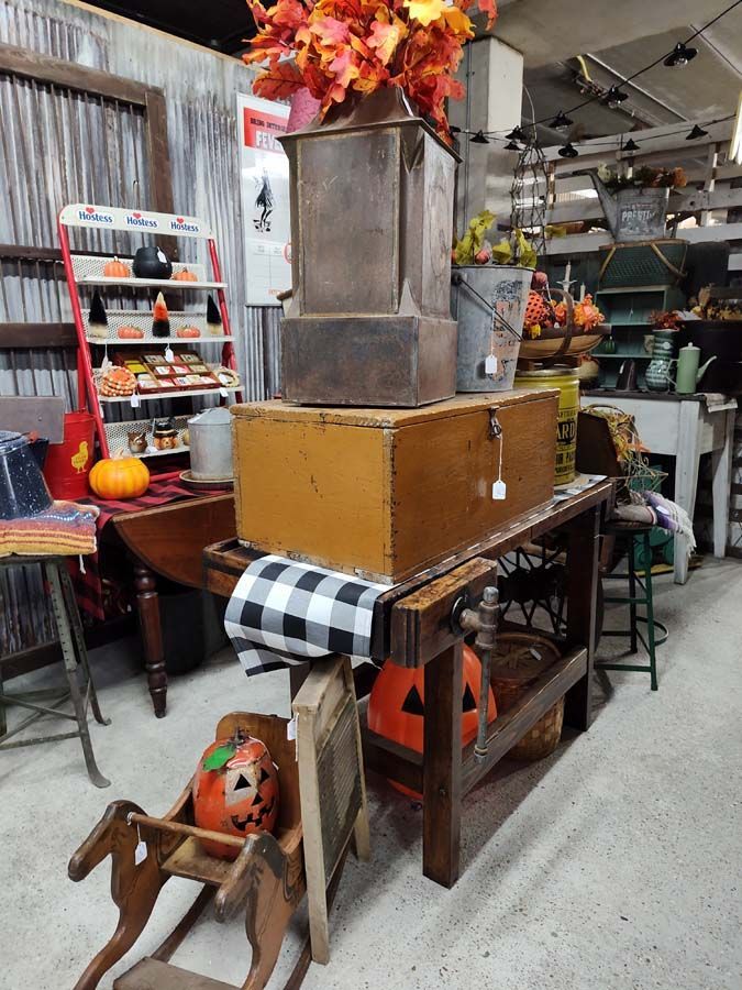 Antique shop display with wooden boxes, pumpkin decor, and fall foliage.