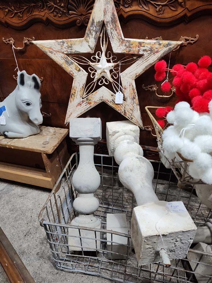 Antique shop display: weathered star, pedestal pieces in wire basket, horse figure, red pom-poms, and cotton.