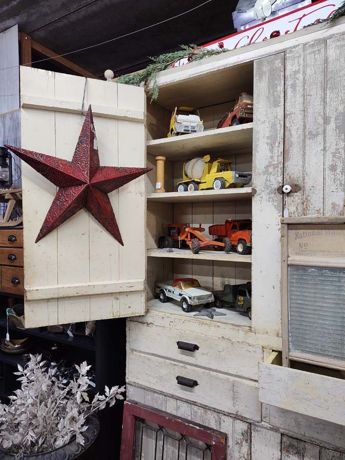 White rustic cabinet with toy trucks and a red star decoration.