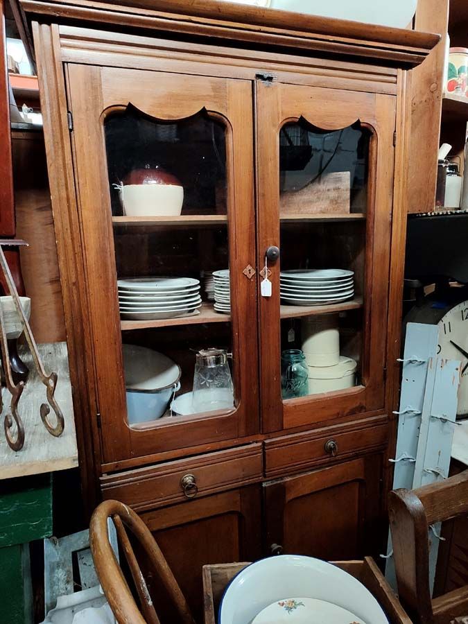 Wooden cabinet with glass doors displaying dishes and bowls.