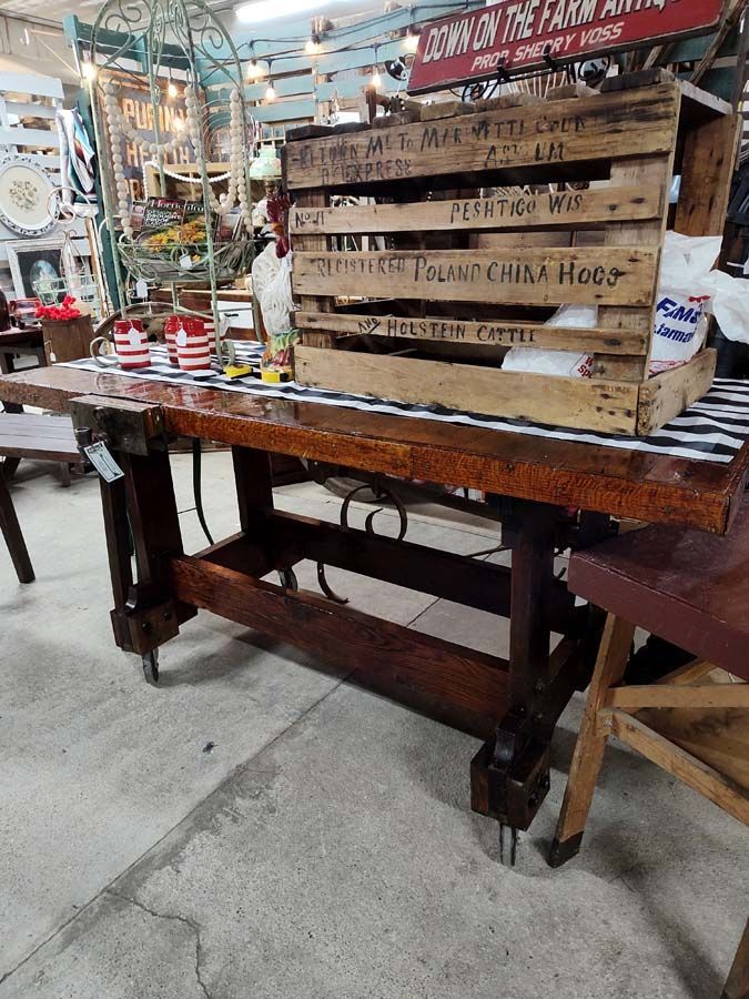 Wooden work table with a crate on top, inside an antique shop.