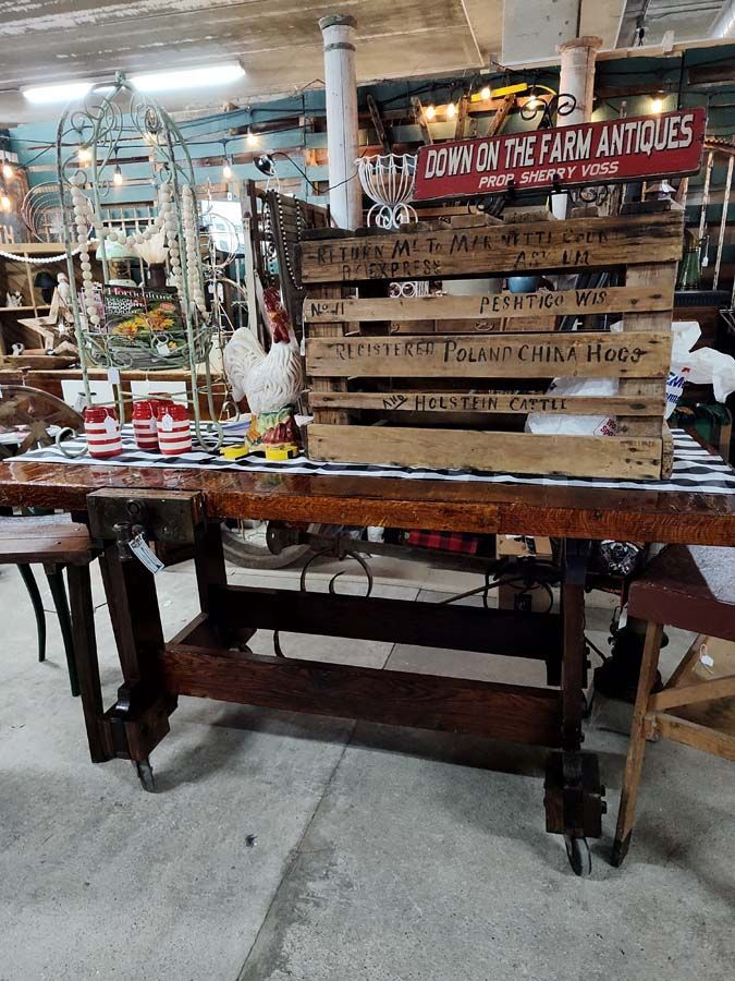 Antique store display featuring a wooden work table, crates, and decorative items. 