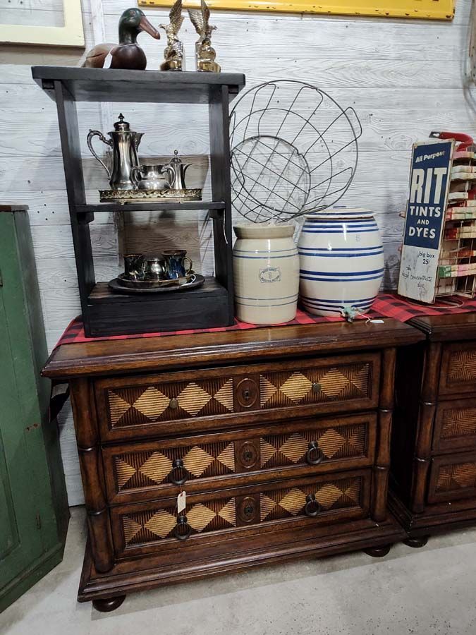 Wooden chest of drawers with decorative carvings, topped with a shelf holding vintage decor.