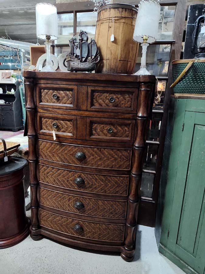Wooden dresser with six drawers, bamboo-style framing, and woven drawer fronts, displayed in an antique shop.