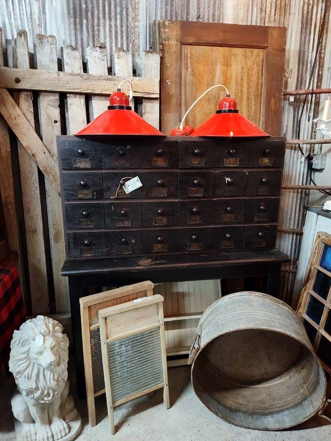Antique wooden cabinet with red lamps, washboards, and metal tub in a rustic setting.