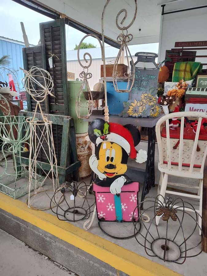 Mickey Mouse Christmas decoration in front of a shop window filled with various items.