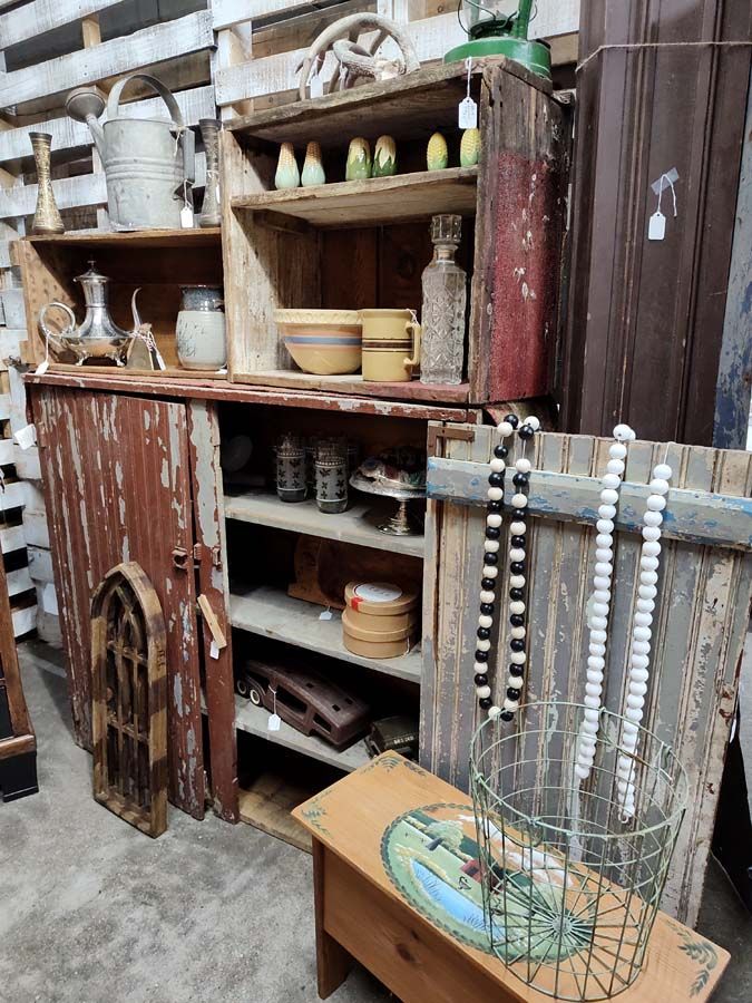 Rustic wooden cabinet with open shelves displaying antique decor. Red and brown hues.