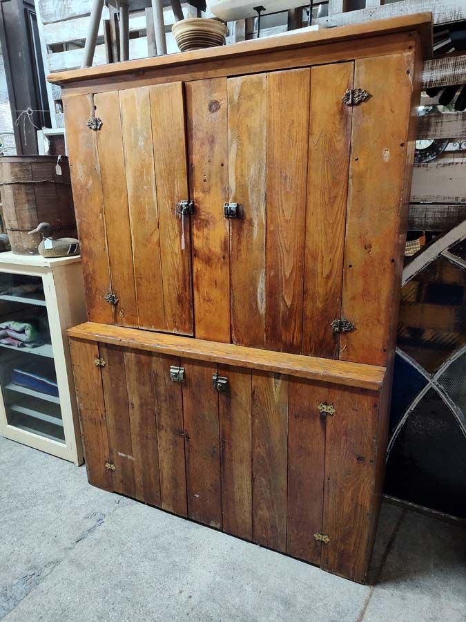 Wooden cabinet with two stacked sections, rustic hardware and a natural wood finish.
