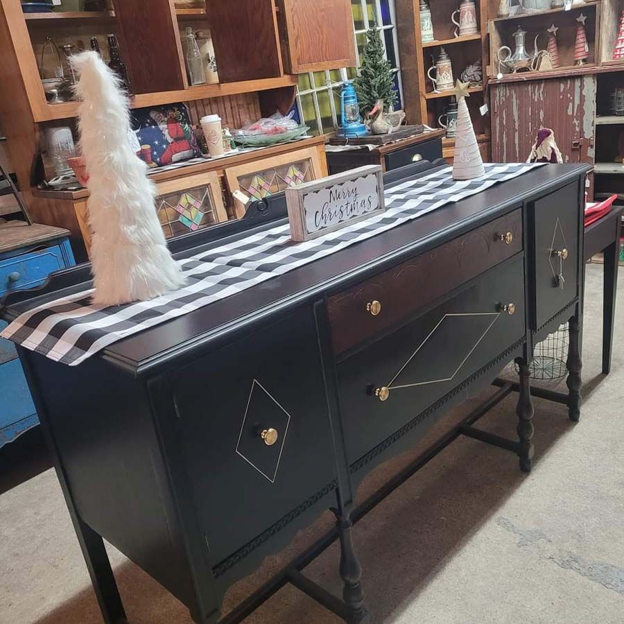 Black buffet table decorated for Christmas with a white tree, a runner, and sign.