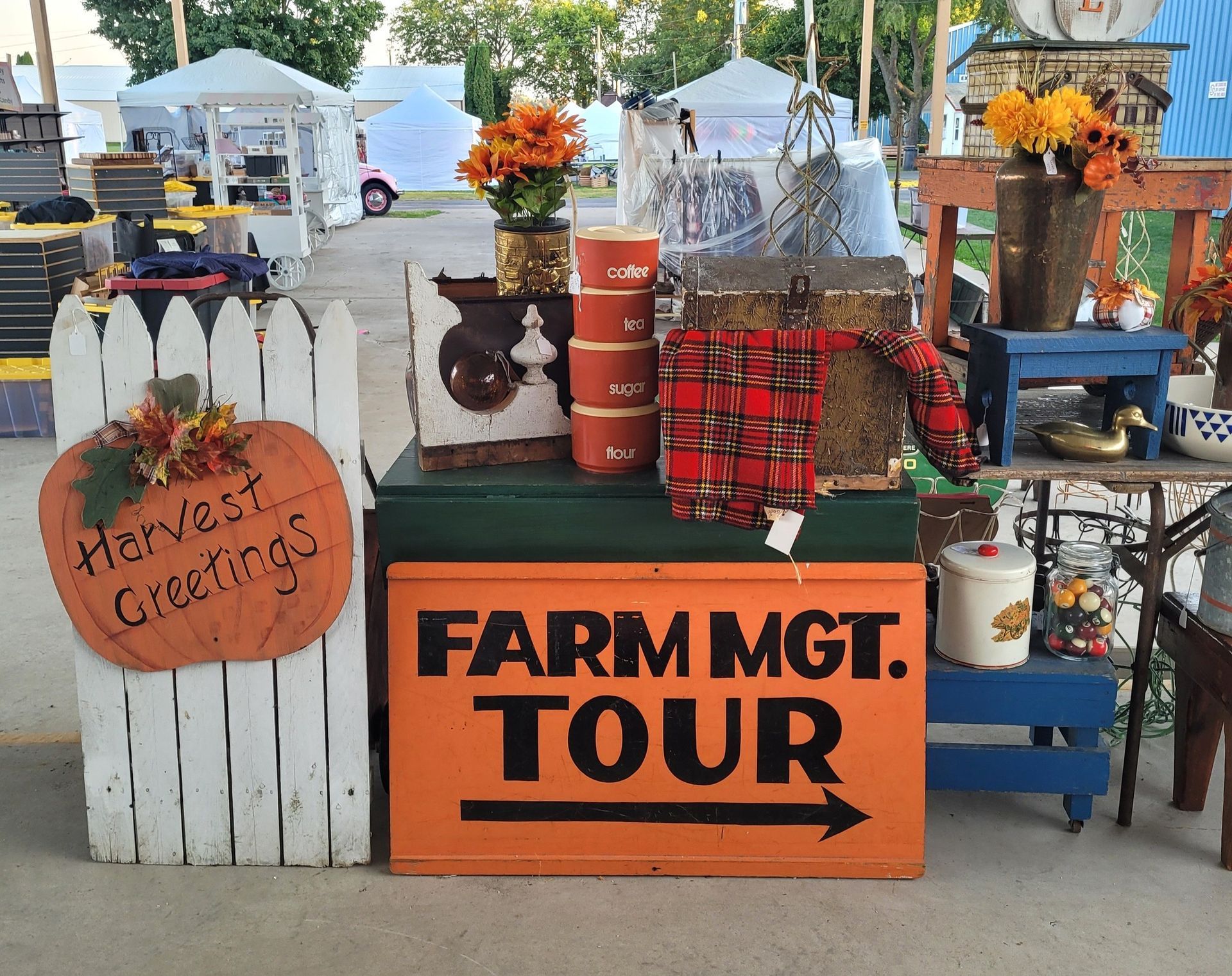 Display of fall decorations and signs for a farm management tour at an outdoor market.