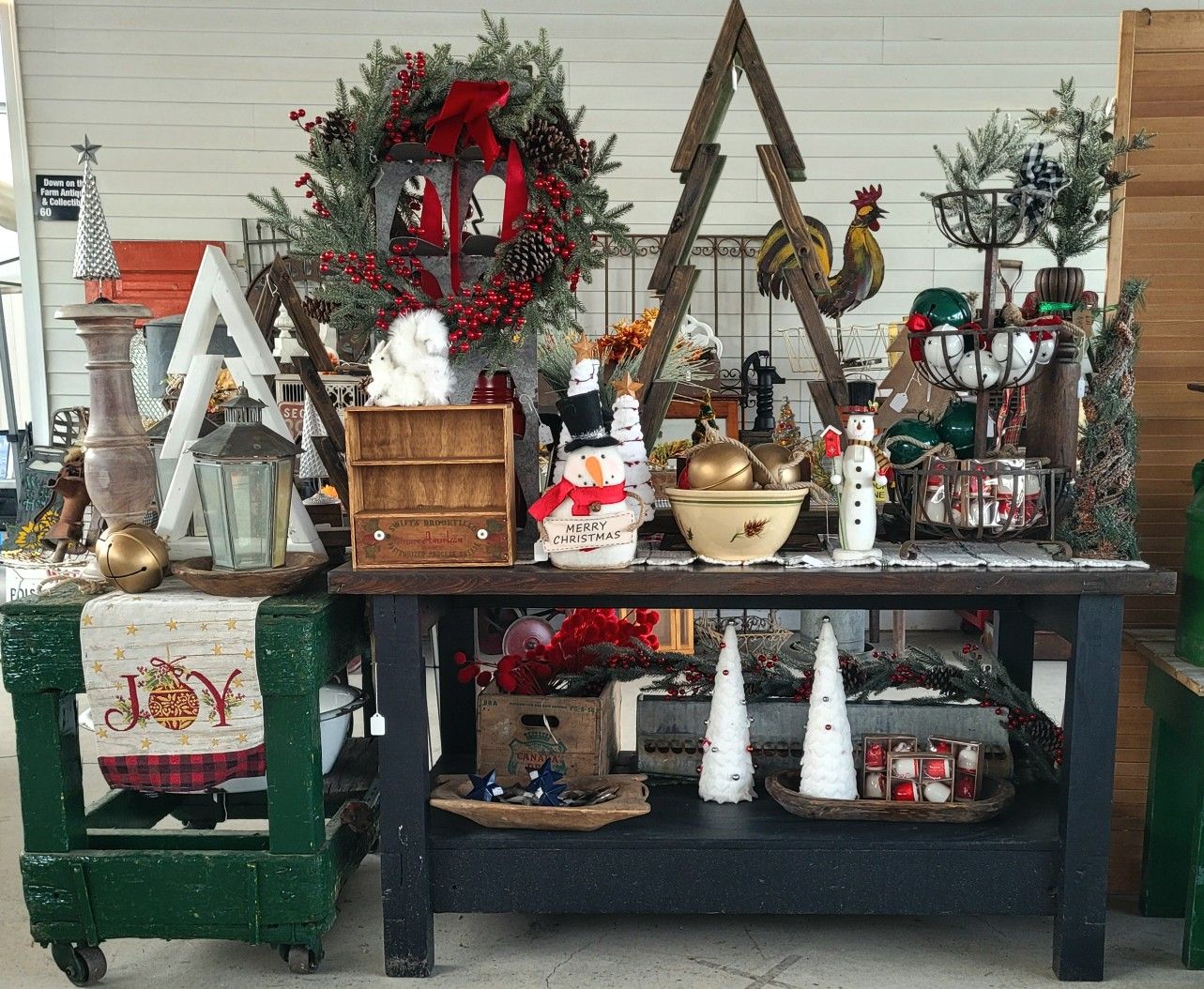Christmas decor display with a wreath, tree-shaped decorations, and a snowman on a rustic table.