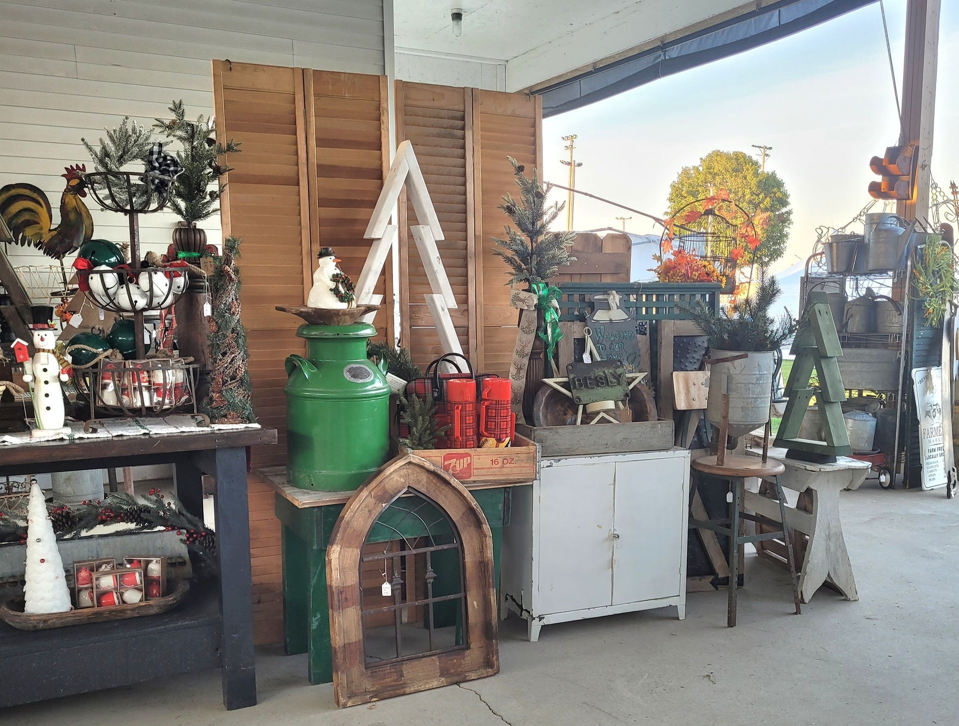 Shop display of rustic Christmas decorations with a green milk can and wooden accents.