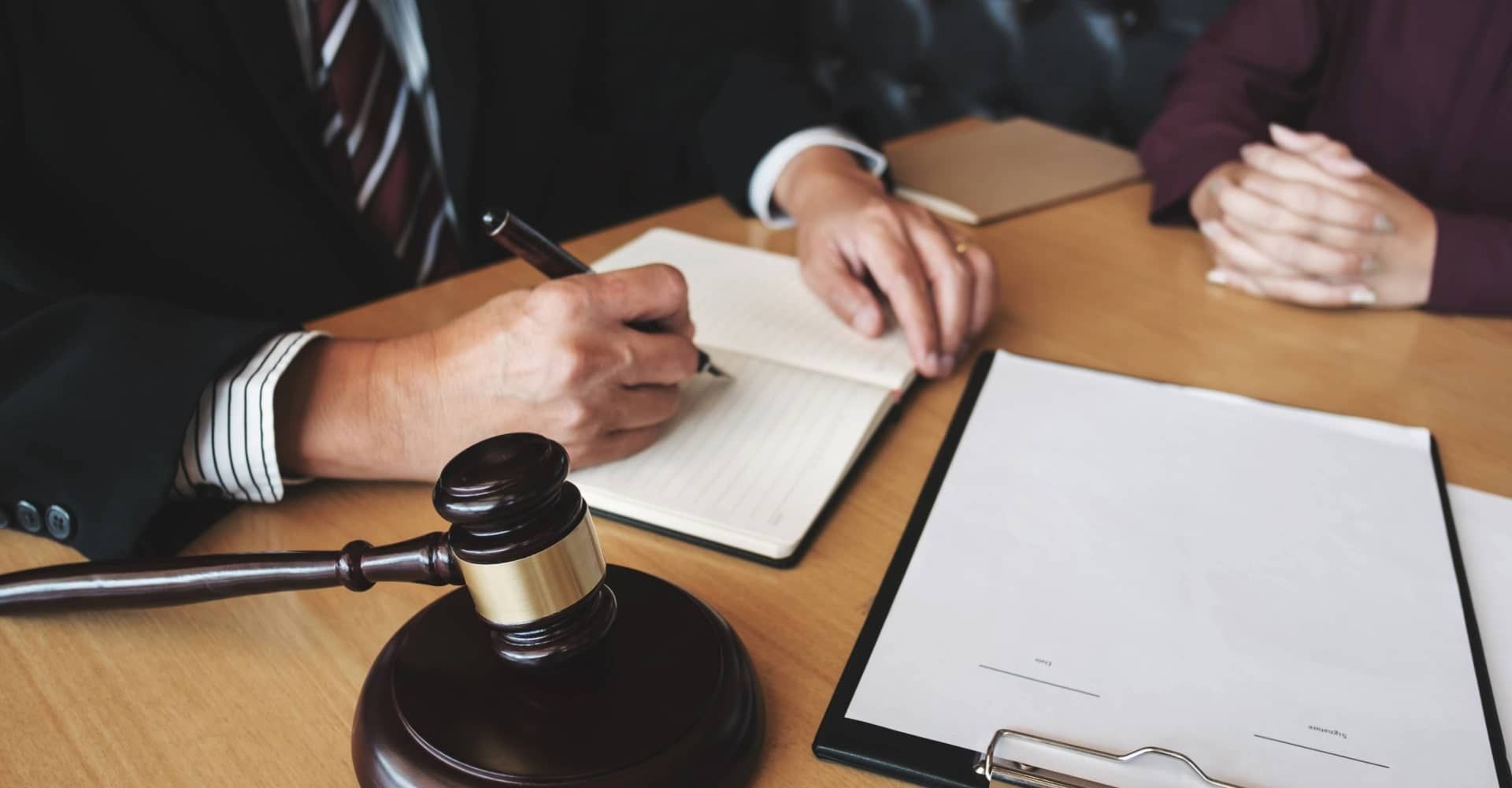A man and a woman are sitting at a table with a judge 's gavel.