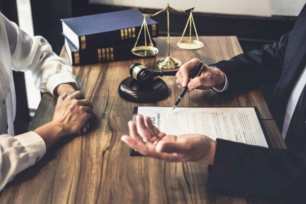 A man and a woman are sitting at a table with a judge 's gavel and scales of justice.