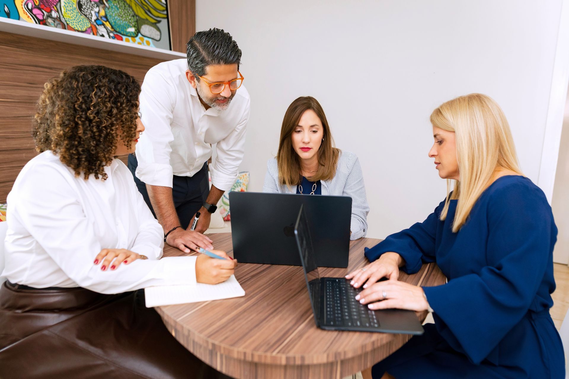 Sinfonica's team in a meeting around a laptop at a round table, discussing work in an office.