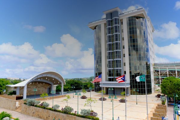 Coastal view of Old San Juan, Puerto Rico, with fortress walls, buildings, and the Atlantic Ocean under a blue sky.