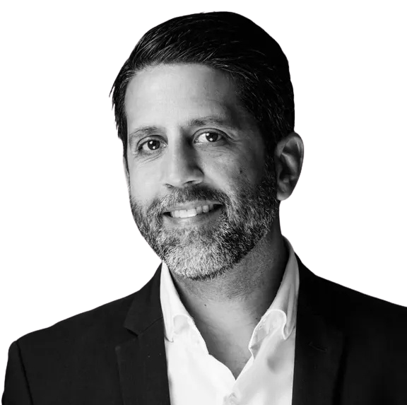 Josean wearing a black blazer and white shirt, smiling, with a pocket square.