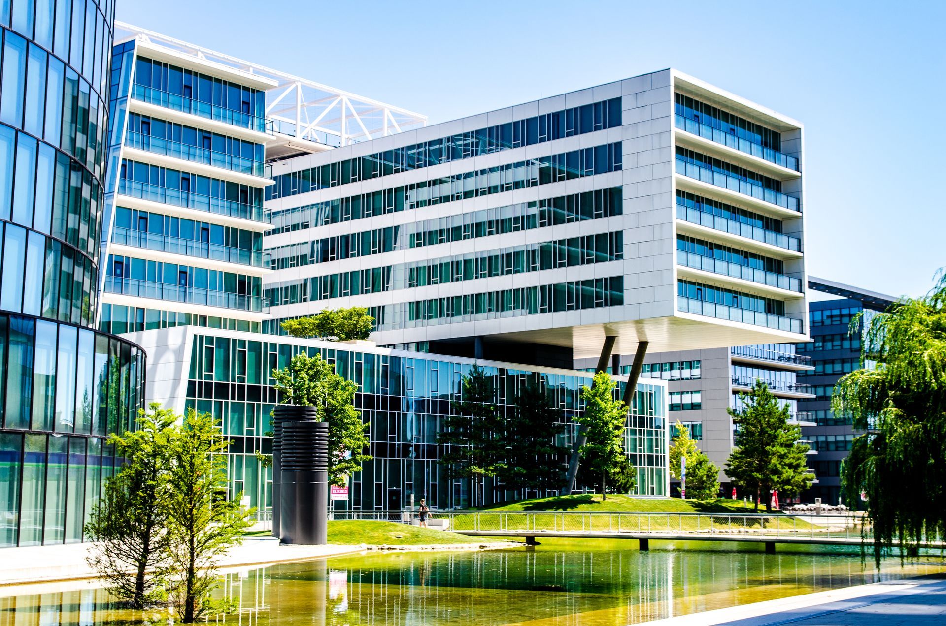 Modern office building with glass facade, white exterior, and a water feature.