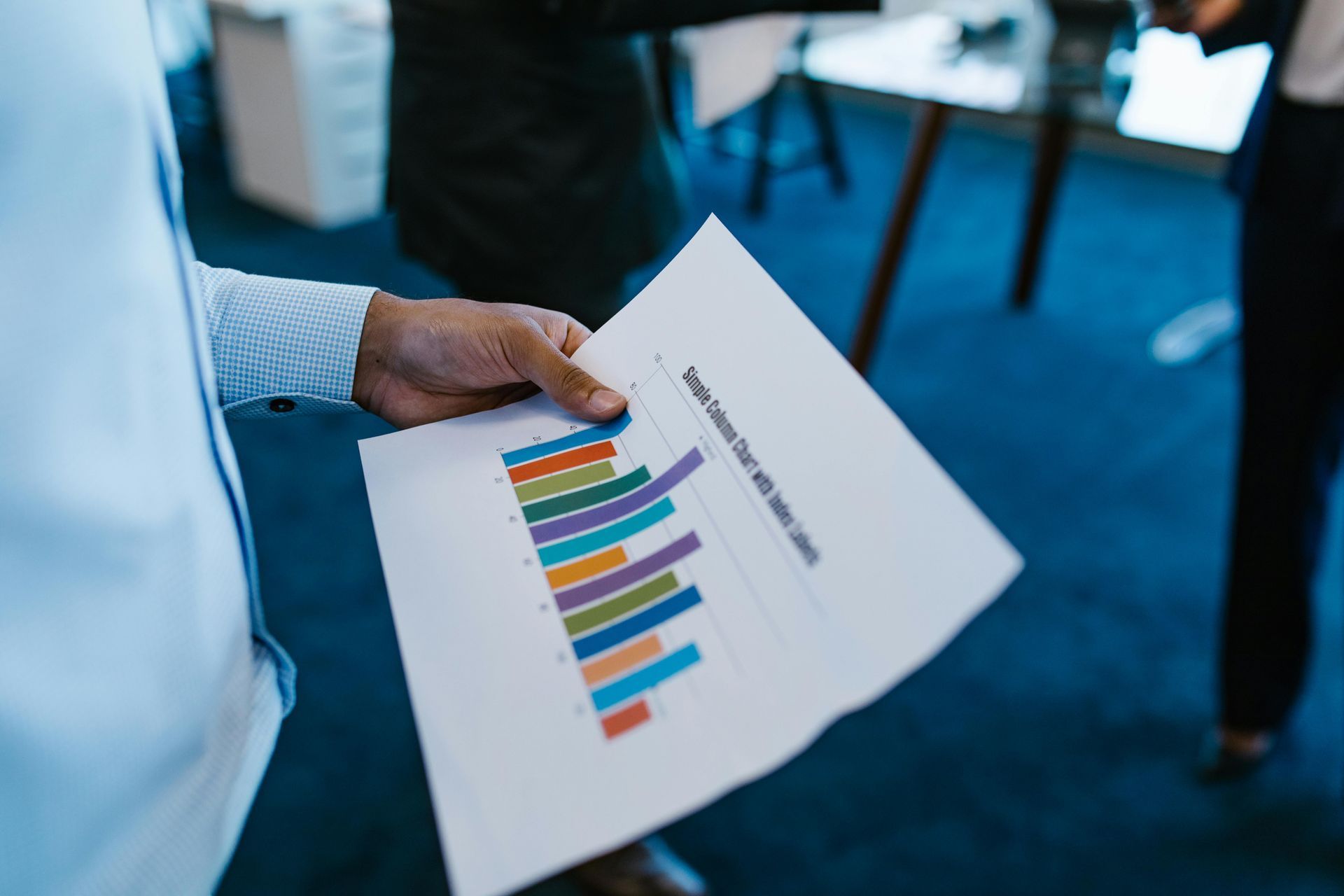 Man holding a business report with a colorful bar graph in an office setting.