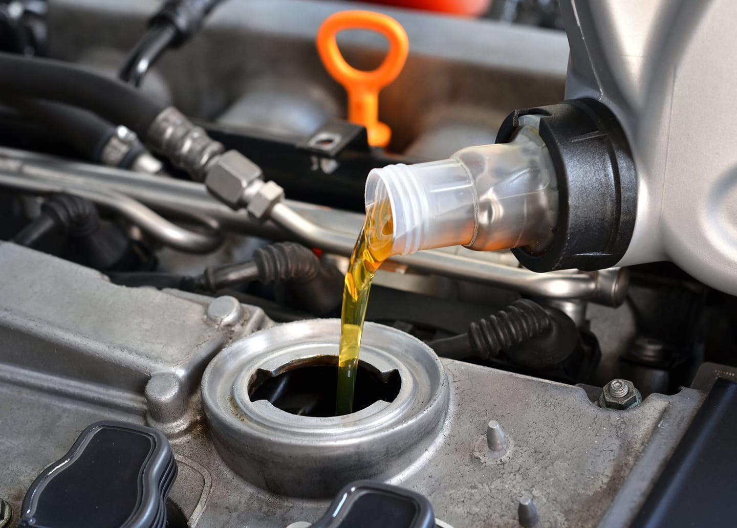 A close up of a person pouring oil into a car engine