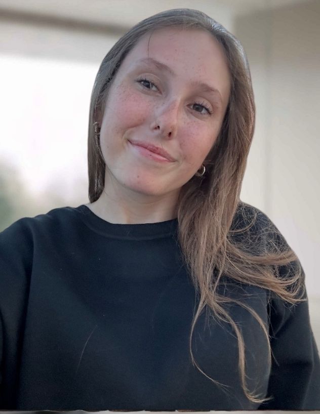 A sign that says `` coming soon '' next to a branch of eucalyptus leaves.