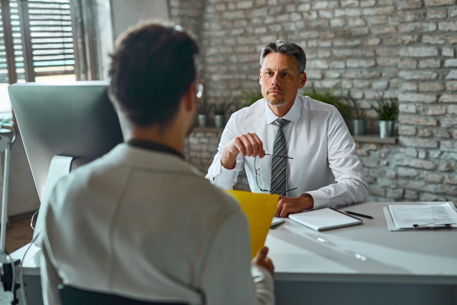 Couple consults with financial advisor at a table. Papers and a laptop are present; they are smiling.