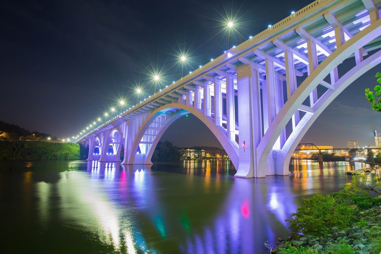 Couple consults with financial advisor at a table. Papers and a laptop are present; they are smiling.