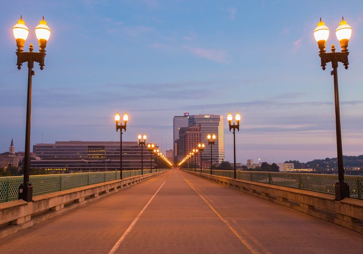 Couple consults with financial advisor at a table. Papers and a laptop are present; they are smiling.