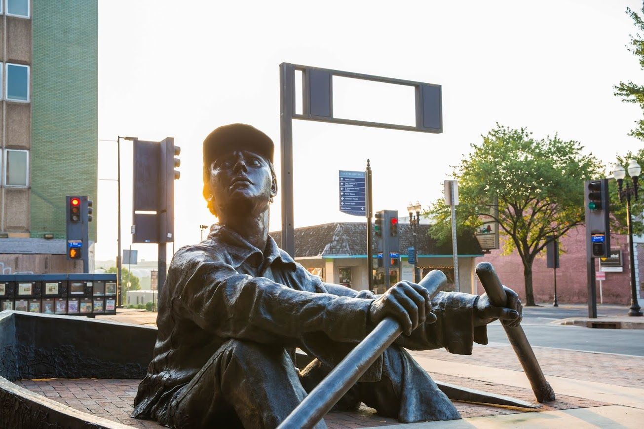 Couple consults with financial advisor at a table. Papers and a laptop are present; they are smiling.