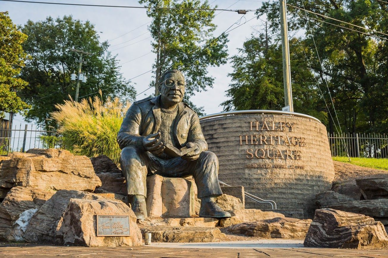 Couple consults with financial advisor at a table. Papers and a laptop are present; they are smiling.