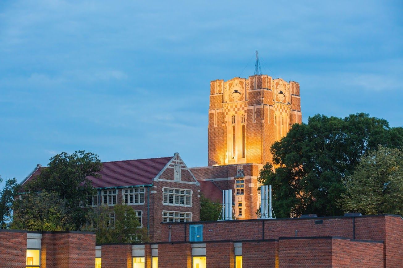 Couple consults with financial advisor at a table. Papers and a laptop are present; they are smiling.