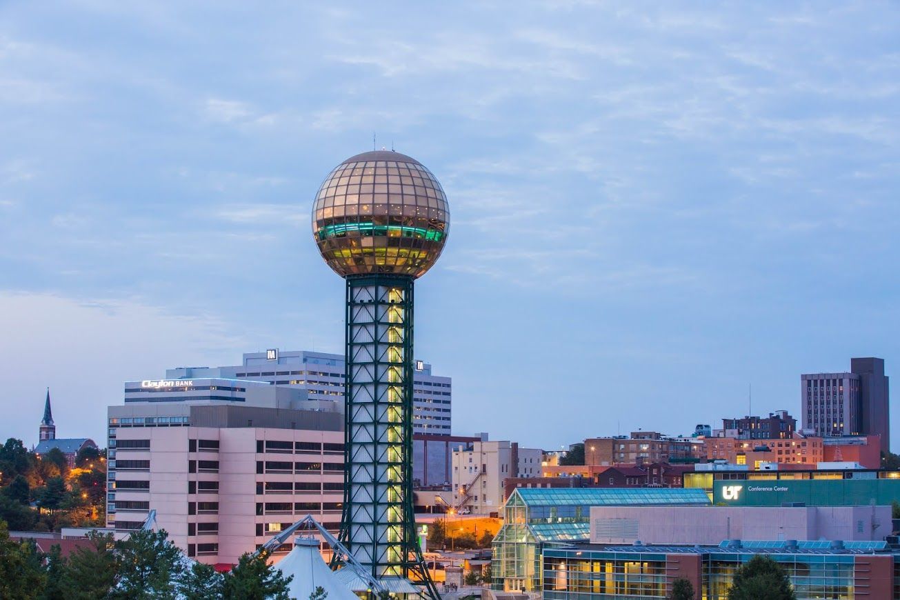 Couple consults with financial advisor at a table. Papers and a laptop are present; they are smiling.