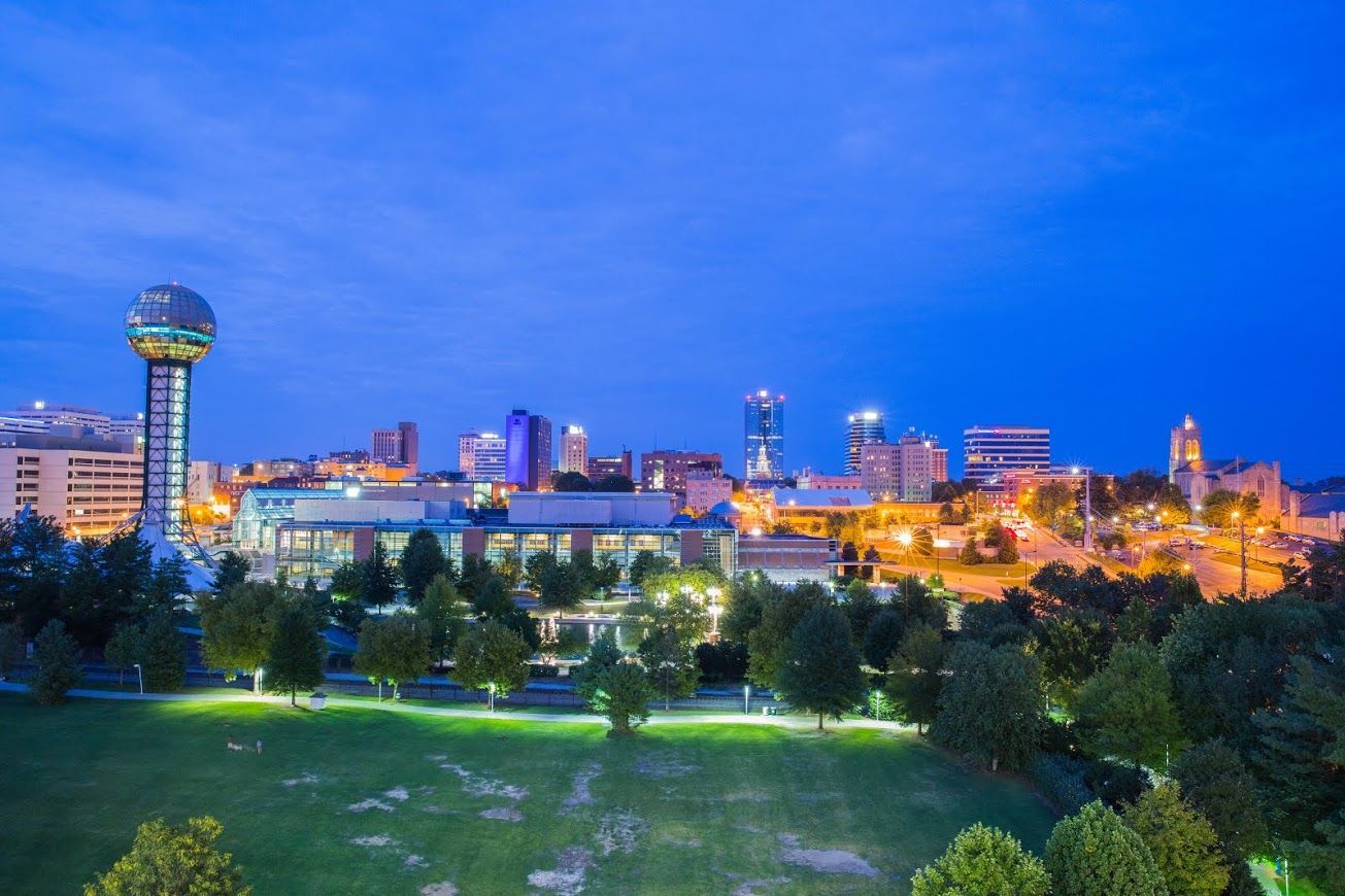 Couple consults with financial advisor at a table. Papers and a laptop are present; they are smiling.