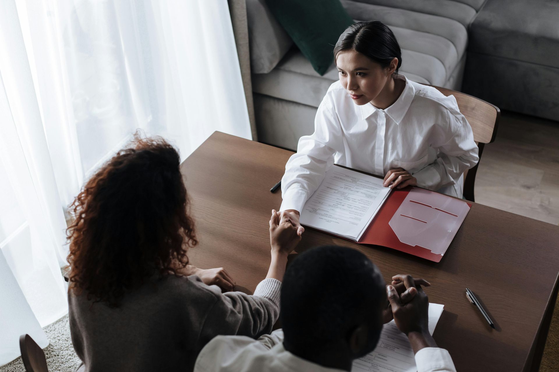 A police officer handcuffs a person at a table, in front of a 