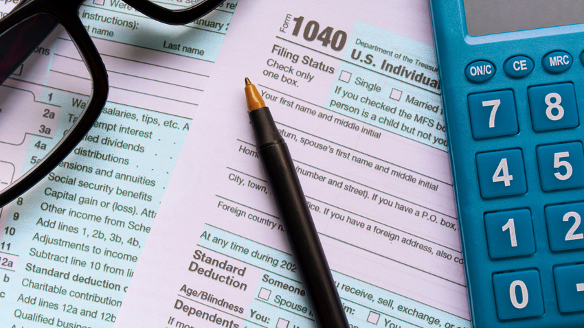 A 1040 tax form with a calculator and glasses on top of it