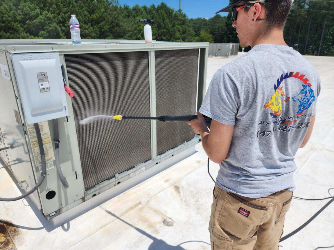 A man is cleaning an air conditioner with a high pressure washer.