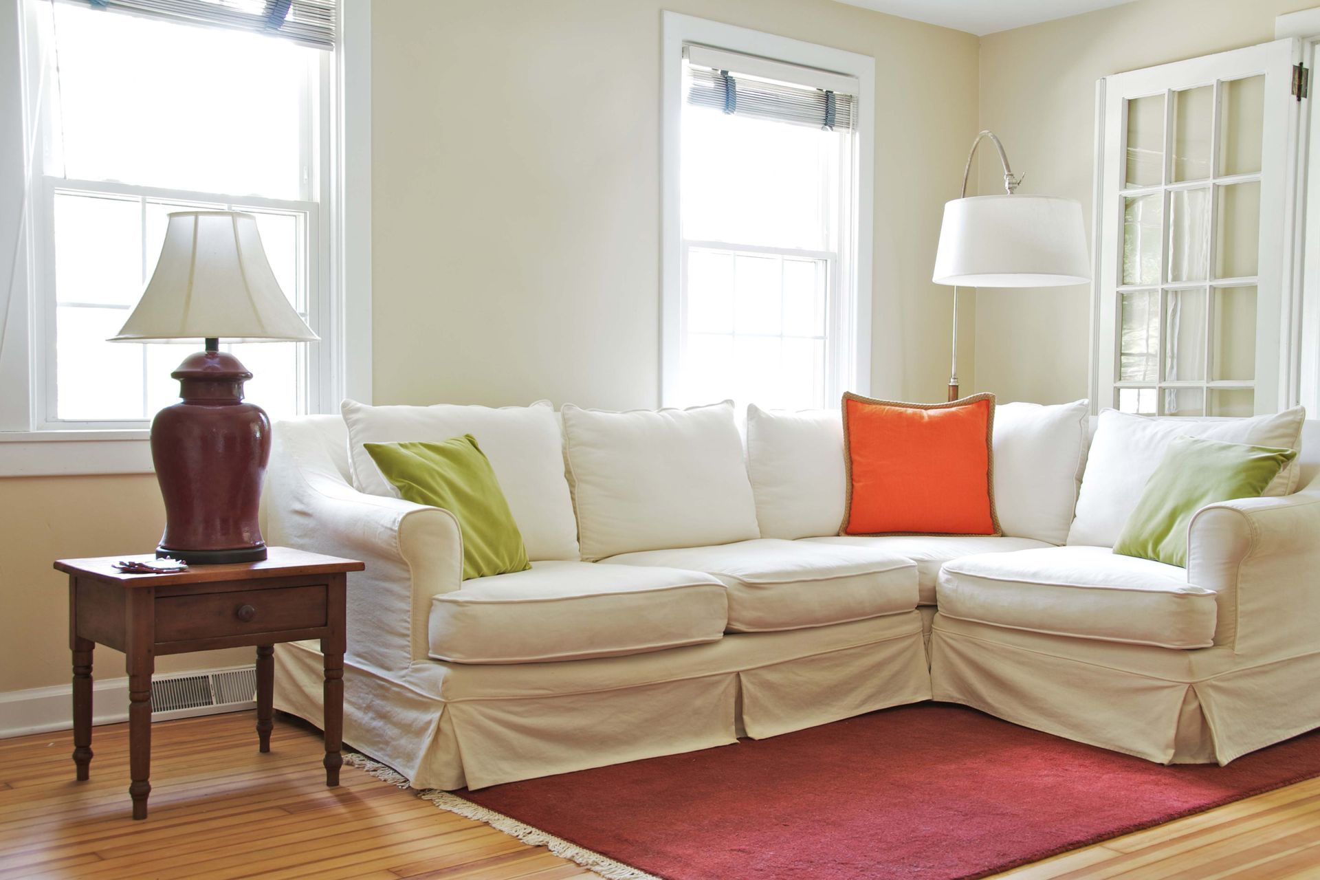 A living room with a white sectional couch and a lamp