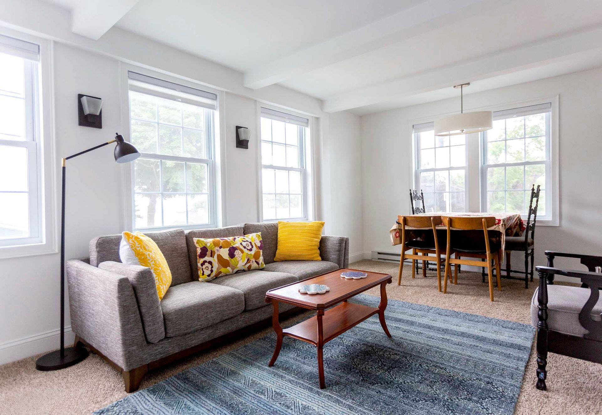 A living room with a couch , coffee table , chair and dining table.