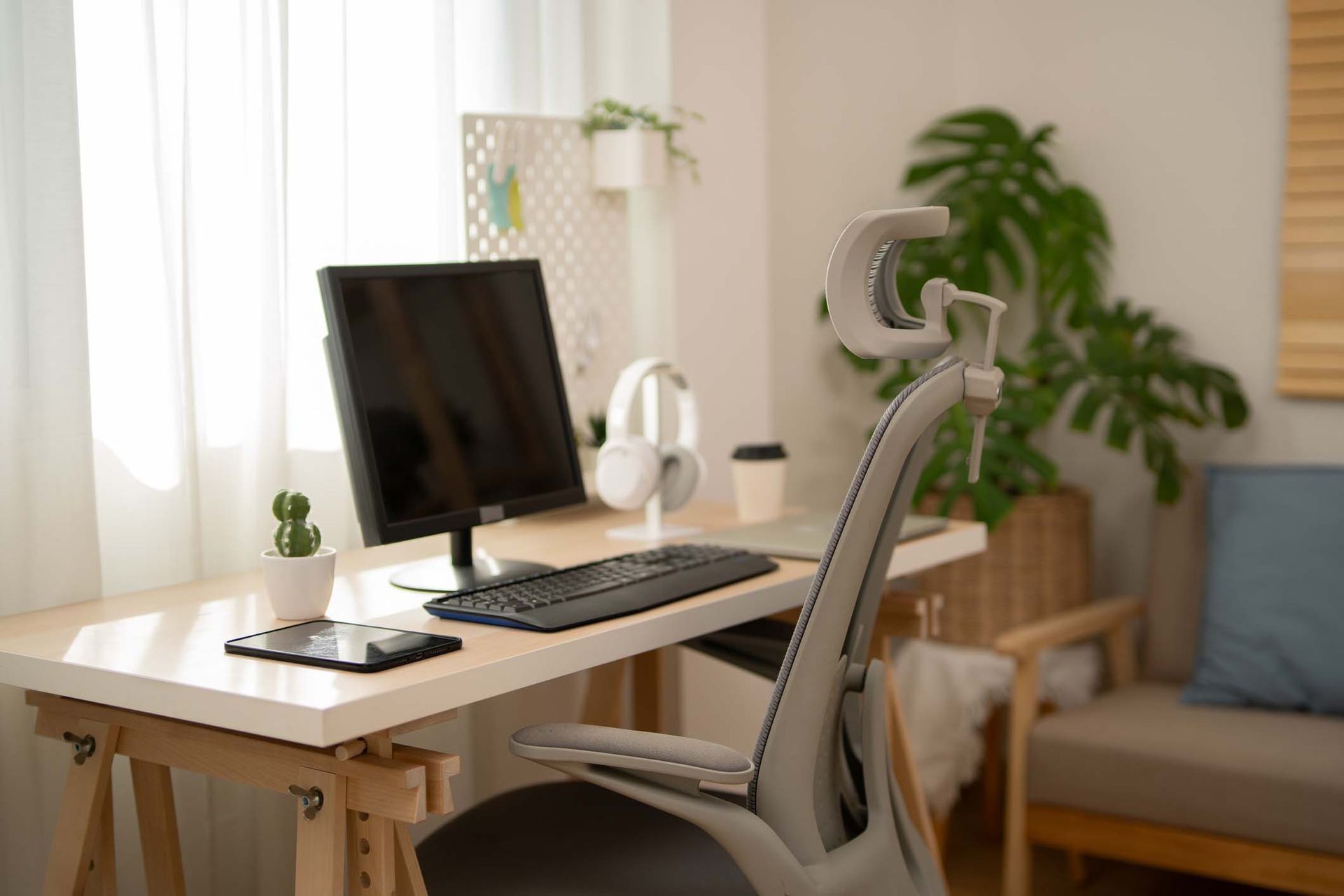 A desk with a computer and headphones on it in a living room