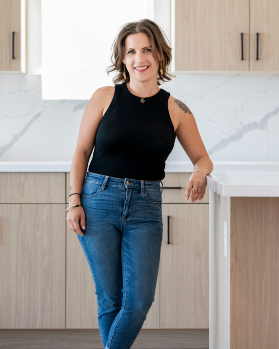 A woman is sitting at a desk with a laptop and a vase of flowers.